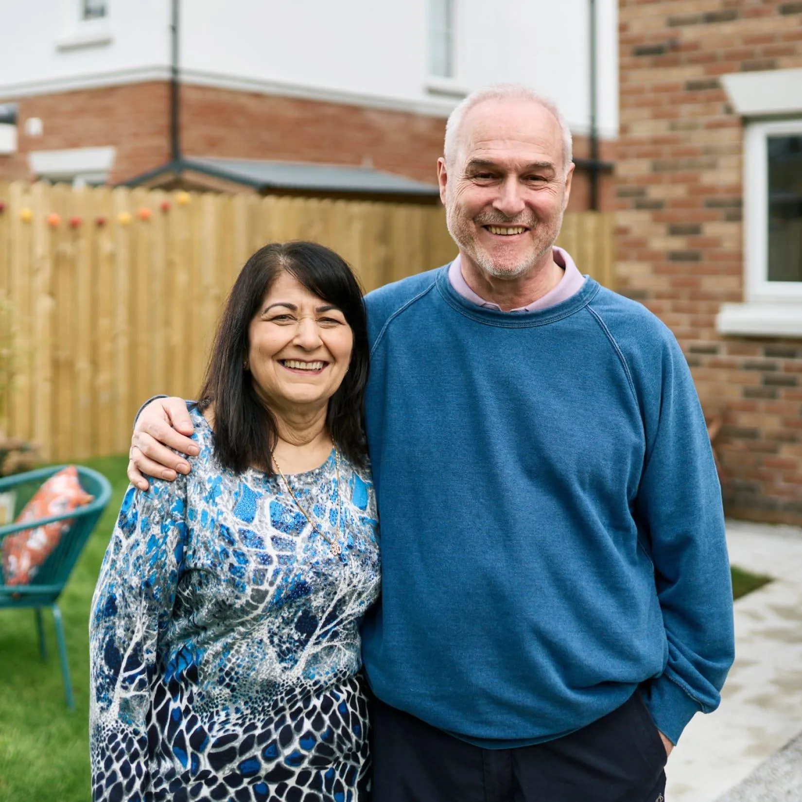 Smiling couple standing together outside their home.