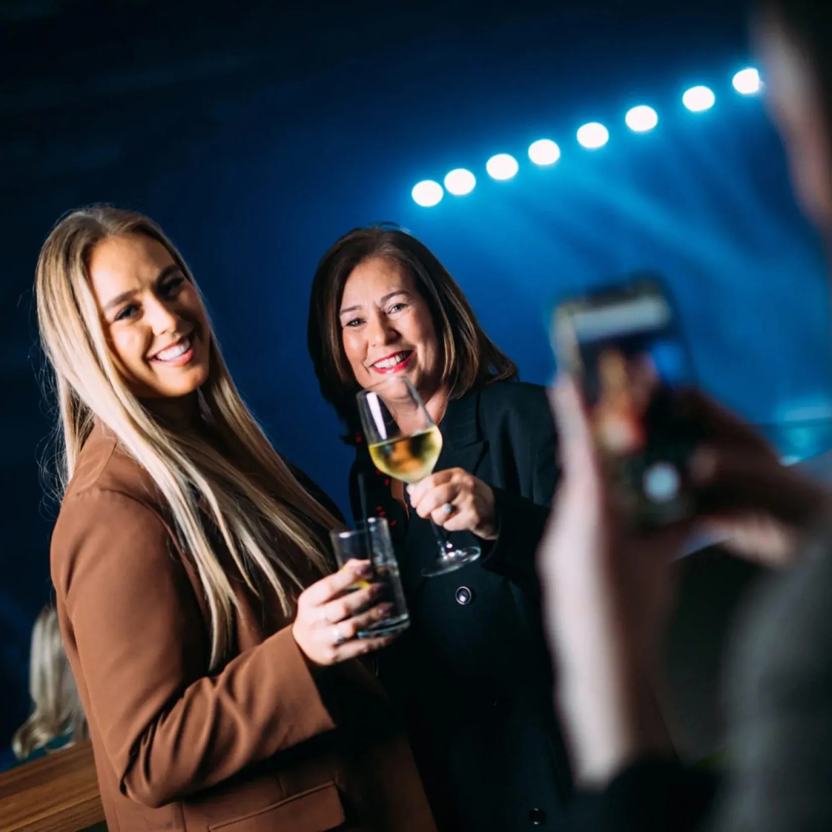 2 women enjoying a concert from suite POV getting their photo taken.